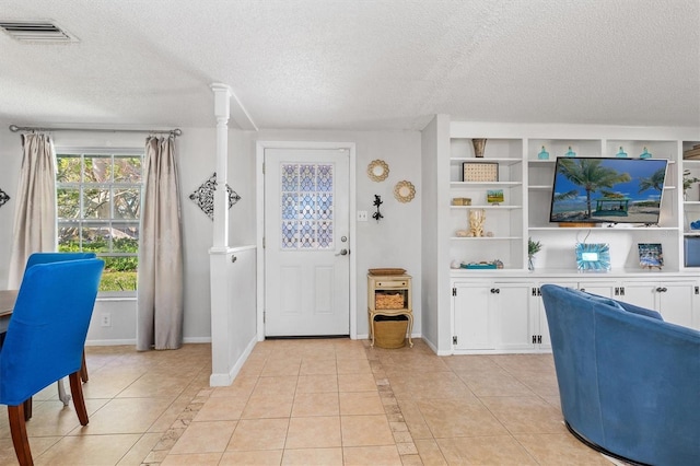 entrance foyer featuring visible vents, a textured ceiling, baseboards, and light tile patterned floors