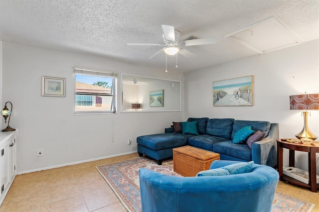 living room featuring a ceiling fan, a textured ceiling, baseboards, and light tile patterned floors