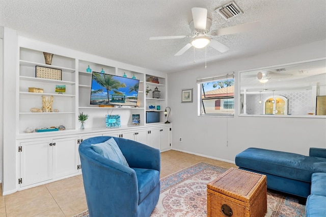 living area featuring built in shelves, light tile patterned floors, visible vents, ceiling fan, and a textured ceiling