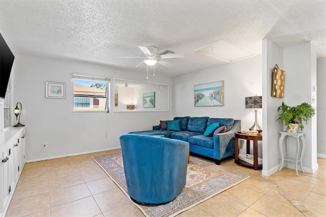 living area with light tile patterned floors, attic access, a textured ceiling, and a ceiling fan