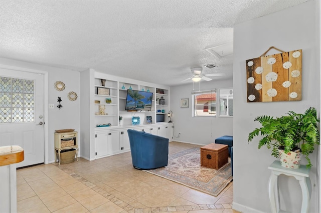 living room featuring attic access, baseboards, a textured ceiling, and light tile patterned flooring