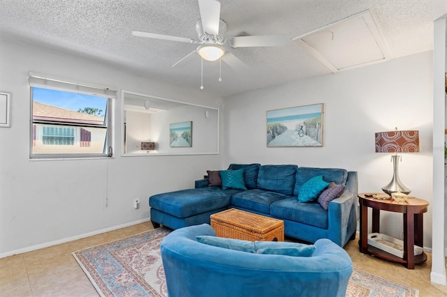 tiled living area featuring a ceiling fan, a textured ceiling, and baseboards