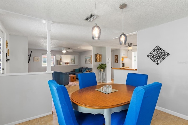 dining space with ceiling fan, light tile patterned floors, a textured ceiling, visible vents, and baseboards