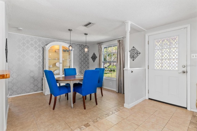 dining space with a textured ceiling, light tile patterned floors, visible vents, baseboards, and wallpapered walls