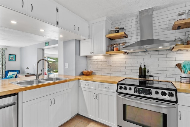 kitchen featuring wall chimney exhaust hood, appliances with stainless steel finishes, open shelves, and wooden counters