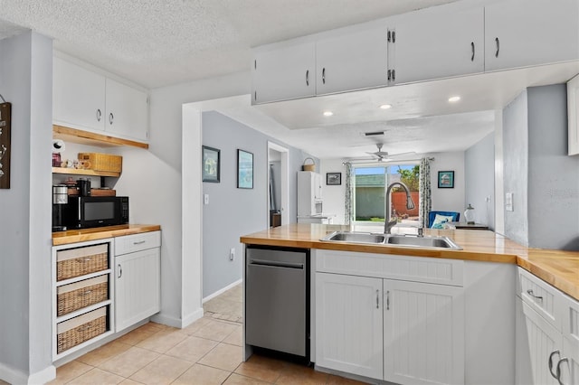 kitchen featuring black microwave, a sink, a textured ceiling, and stainless steel dishwasher