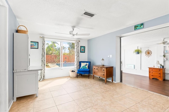 sitting room with ceiling fan, light tile patterned floors, a textured ceiling, and visible vents