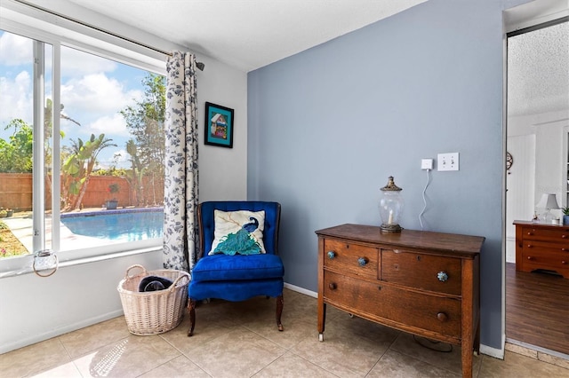 sitting room featuring a wealth of natural light, tile patterned flooring, a textured ceiling, and baseboards