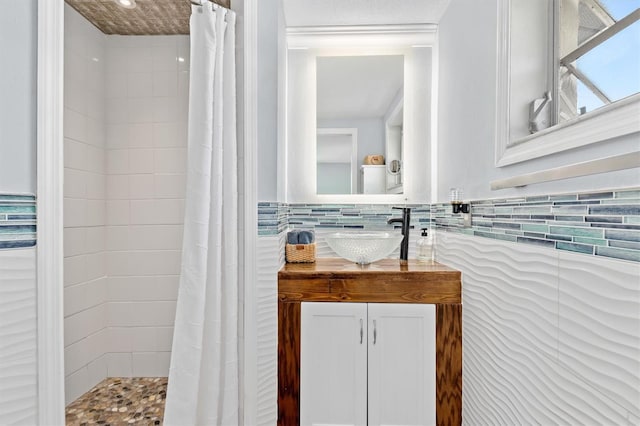 full bath featuring vanity, tile walls, and tiled shower