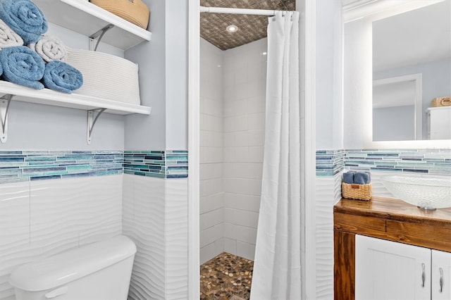 bathroom featuring tiled shower, tile walls, toilet, and vanity