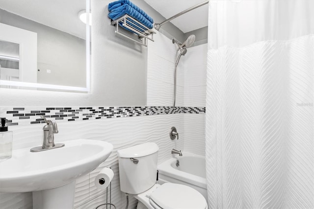 bathroom with a sink, shower / tub combo, toilet, and tile walls