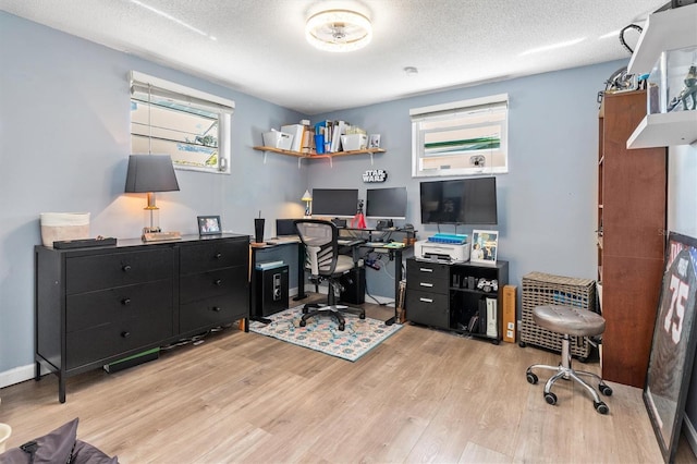 home office with a textured ceiling, light wood-type flooring, and baseboards