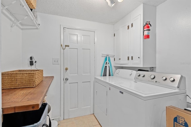 washroom featuring a textured ceiling, washing machine and clothes dryer, and light tile patterned floors