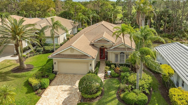 view of front facade featuring driveway, a tile roof, an attached garage, and a front yard