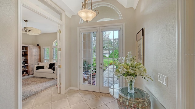 entryway with light tile patterned floors, a textured wall, french doors, and baseboards