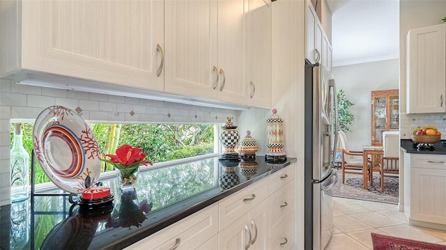 kitchen featuring light tile patterned flooring, stainless steel fridge with ice dispenser, decorative backsplash, dark countertops, and crown molding