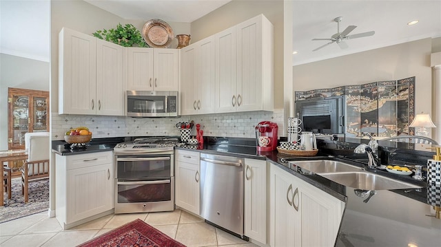 kitchen with stainless steel appliances, a sink, ornamental molding, decorative backsplash, and dark countertops