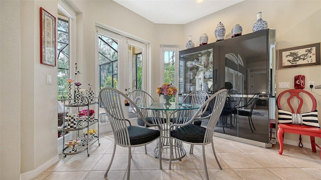 tiled dining space featuring french doors and baseboards