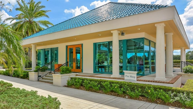 property entrance featuring a tiled roof, french doors, and stucco siding