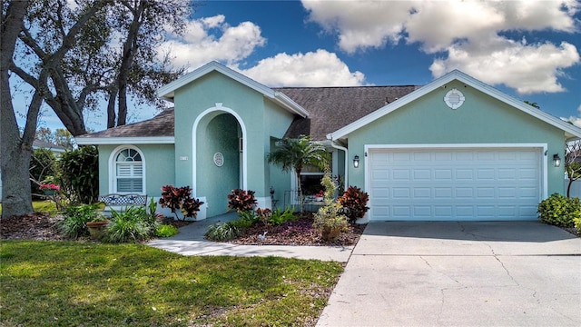 view of front facade with an attached garage, a shingled roof, concrete driveway, stucco siding, and a front lawn