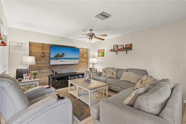 living room featuring a ceiling fan, visible vents, and wooden walls