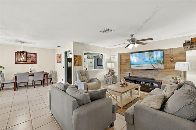 living room with ceiling fan, wooden walls, visible vents, and light tile patterned flooring