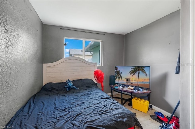 bedroom with a textured wall, baseboards, and wood finished floors