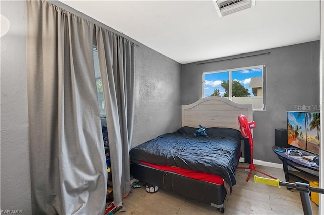 bedroom featuring baseboards, visible vents, and wood finished floors