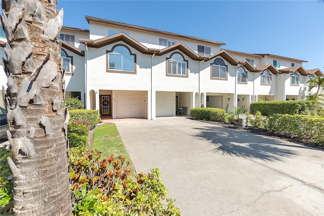 view of property with a garage, driveway, and stucco siding