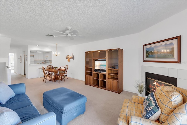 living area with light colored carpet, visible vents, a fireplace, and a textured ceiling