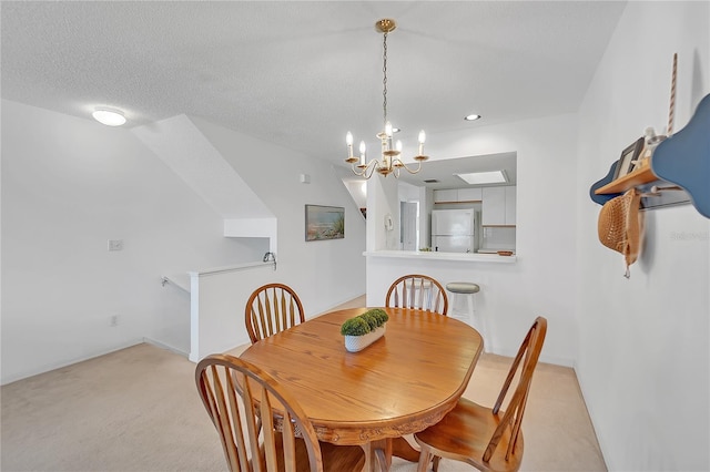 dining space with a chandelier, light colored carpet, and a textured ceiling