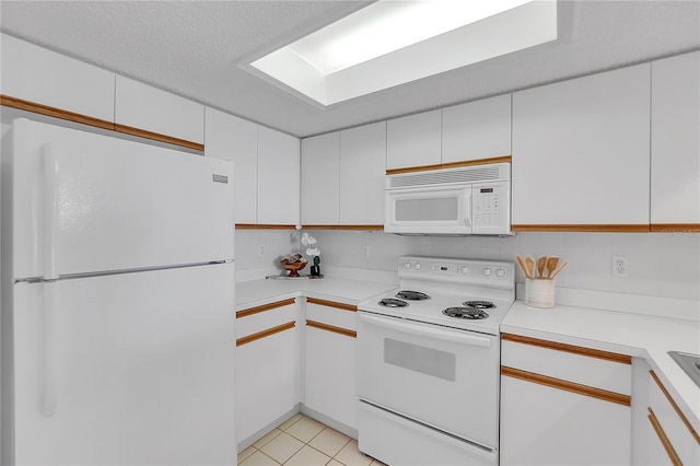 kitchen with light tile patterned floors, a textured ceiling, white appliances, white cabinets, and light countertops