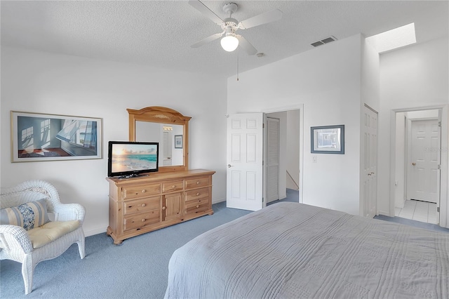 bedroom with a textured ceiling, carpet floors, ceiling fan, and visible vents