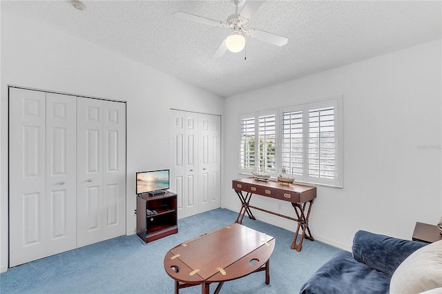 interior space featuring lofted ceiling, carpet, a ceiling fan, and a textured ceiling