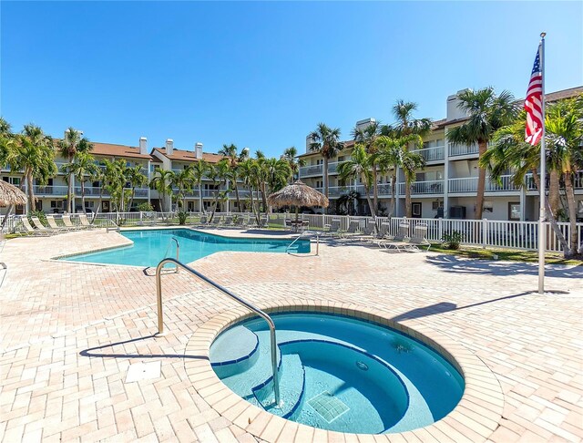 community pool featuring a patio area, fence, and a hot tub