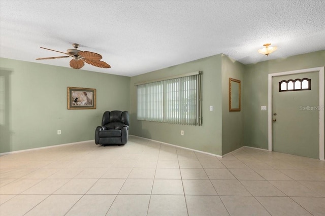 foyer entrance with a textured ceiling, baseboards, a ceiling fan, and light tile patterned flooring