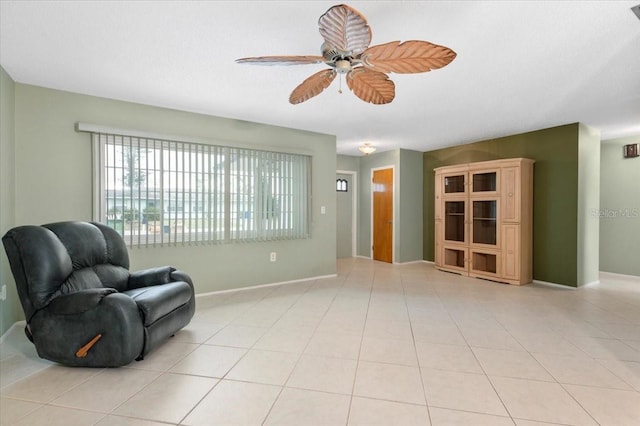 living area featuring light tile patterned floors, ceiling fan, and baseboards