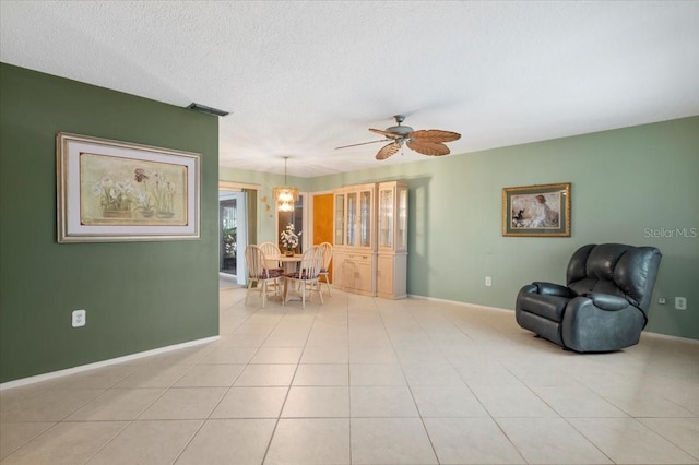 sitting room featuring light tile patterned floors, a textured ceiling, a ceiling fan, and baseboards