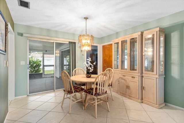 dining space with a textured ceiling, a chandelier, light tile patterned flooring, visible vents, and baseboards