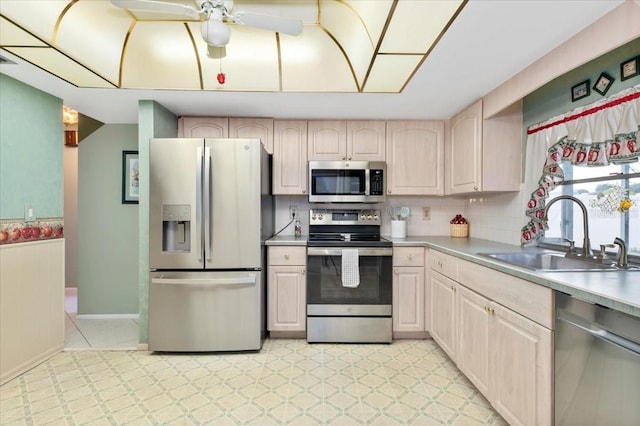 kitchen featuring a wainscoted wall, a sink, light countertops, appliances with stainless steel finishes, and light floors