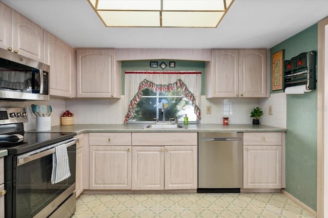 kitchen with light floors, light countertops, appliances with stainless steel finishes, light brown cabinets, and a sink