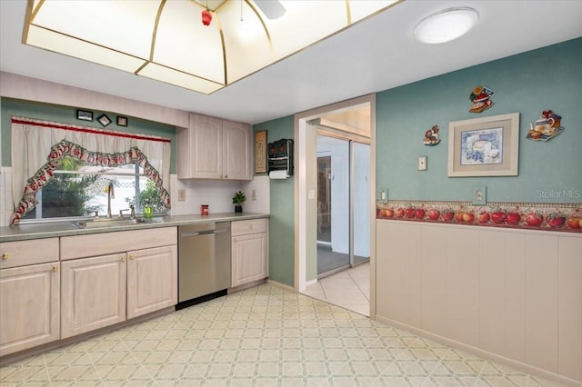 kitchen with a wainscoted wall, light floors, light countertops, a sink, and dishwasher