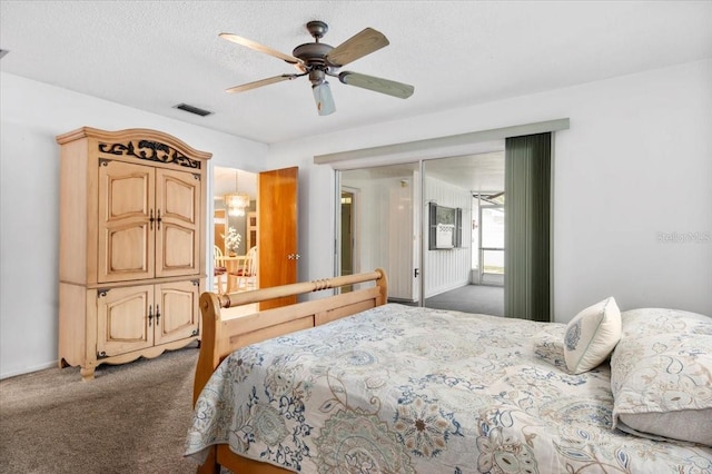 carpeted bedroom with visible vents, ceiling fan, and a textured ceiling