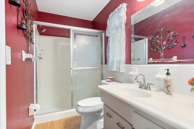 bathroom featuring toilet, a shower stall, wood finished floors, and vanity