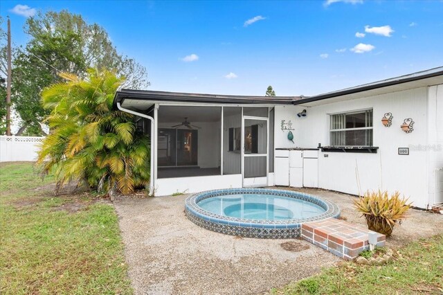 rear view of property with a sunroom, fence, and an in ground hot tub