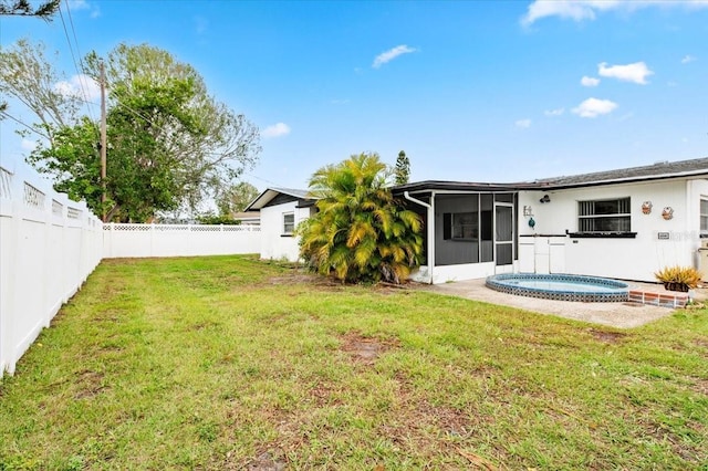 rear view of house with a yard, an outdoor hot tub, a fenced backyard, and a sunroom