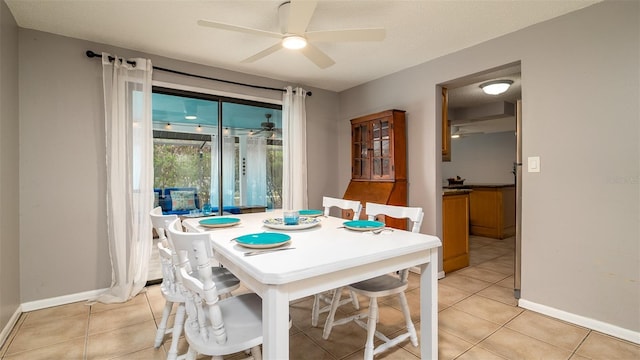 dining space with a ceiling fan, a textured ceiling, baseboards, and light tile patterned floors