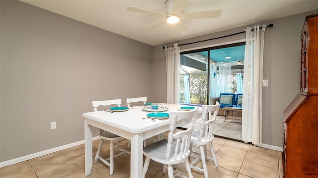 dining area featuring a ceiling fan, light tile patterned flooring, and baseboards