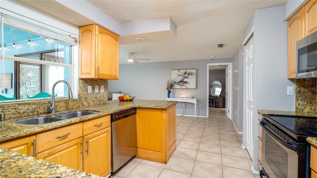 kitchen featuring visible vents, decorative backsplash, light stone counters, stainless steel appliances, and a sink