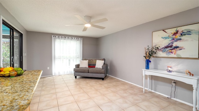 sitting room featuring light tile patterned floors, ceiling fan, baseboards, and a textured ceiling